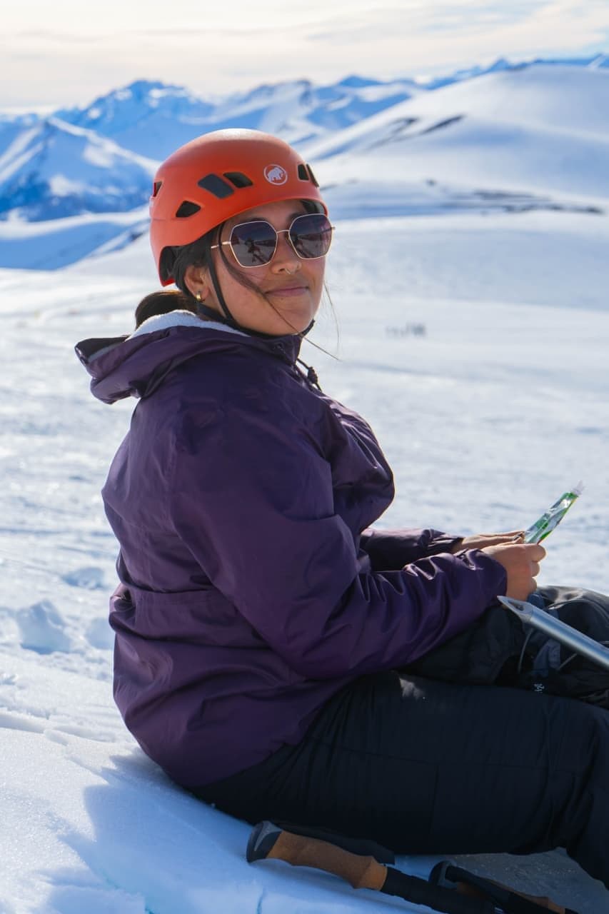 Karen Reyes sentada en la nieve con la cordillera detrás
