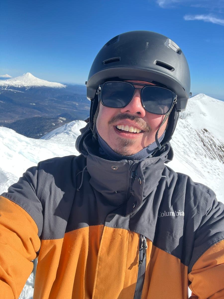 Patricio García en una cumbre nevada, con un volcán al fondo